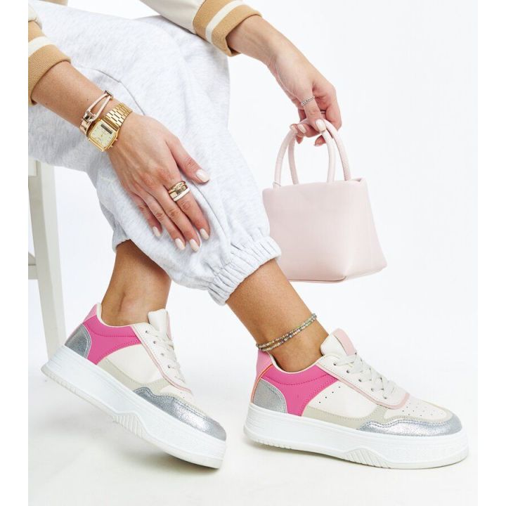 Baltos ir rožinės spalvos sportbačiai ant grubaus Rumai pado